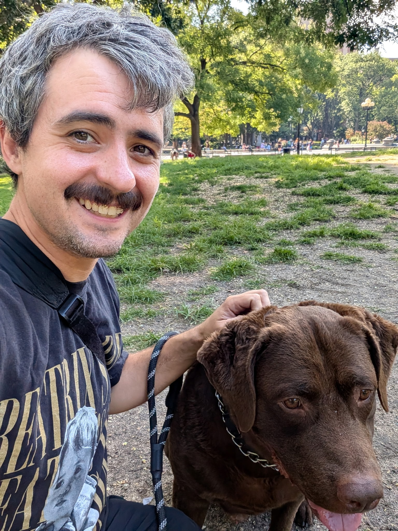David, lead walker and founder, smiling beside a chocolate lab on a walk in the park